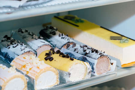 Elongated cakes inside a fridge in a pastry shop.の写真素材