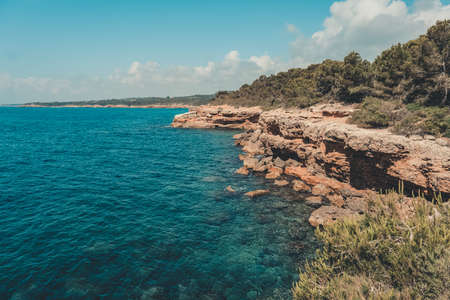 Rocky shore with a small cliff in the sea.の写真素材