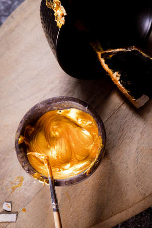 Bowl with a golden ointment to repair a pottery for the practice of kintsugi art.の写真素材