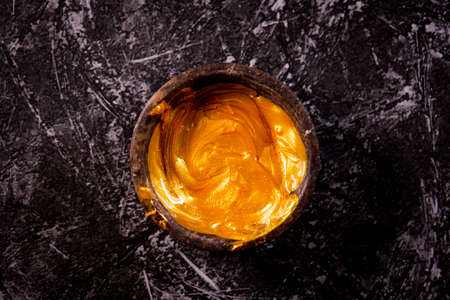 Golden ointment in a bowl on a gray marble background.の写真素材