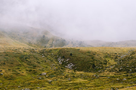 Mountainous landscape with hills and clouds around it.
