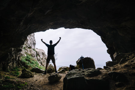 Man at the entrance of a backlit cave.の写真素材