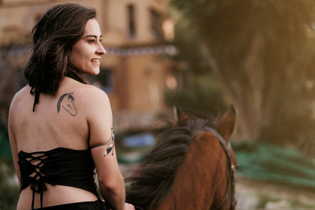 Rider girl with back dreadlocks riding a horse.
