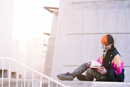 Urban looking boy reading on the streetの写真素材