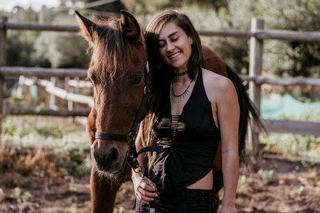 Brunette woman posing looking at the camera next to a brown horse.の写真素材