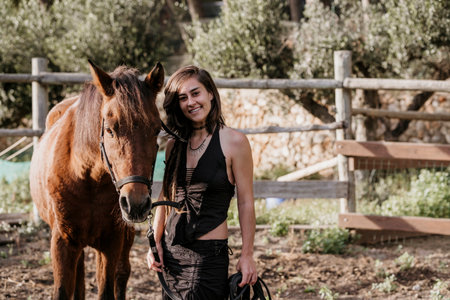 Brunette woman posing looking at the camera next to a brown horse.の写真素材