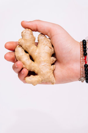 Close up of a ginger root being held in hand and against a white background.の写真素材