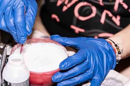 Person with gloves preparing the mixture to apply a dye to the hair.の写真素材