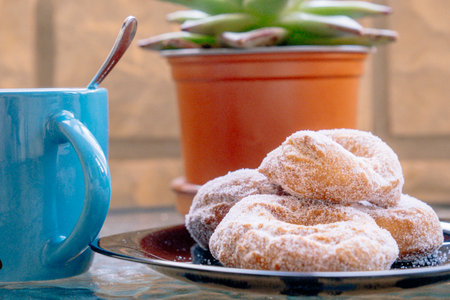 Group of homemade donuts next to a blue cup.の写真素材