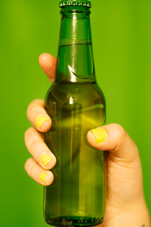 A girl holding a bottle of green beer.の写真素材