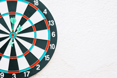 Target on a wall with darts stuck in the center and white backgroundの写真素材