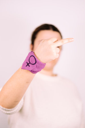 Feminism concept. She girl raising a finger with a lilac bracelet.の写真素材