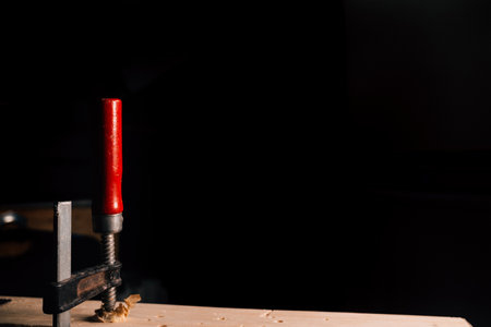 Wood clamp with red handle and dark background.の写真素材