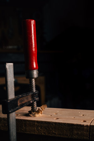 Wood clamp with red handle and dark background.の写真素材
