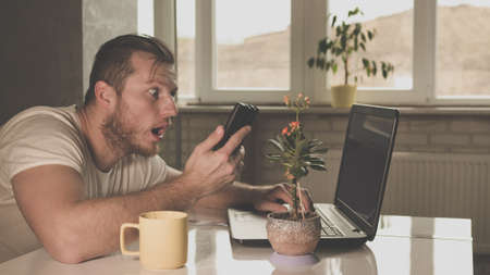 surprised message on the phone laptop in the kitchenの写真素材