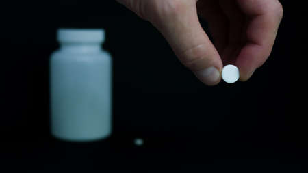 Close up of a white tablet in a male hand. Taking vitamins to maintain immunityの写真素材