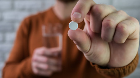 Close-up of a white pill in a man's hand. Man takes care of his healthの写真素材