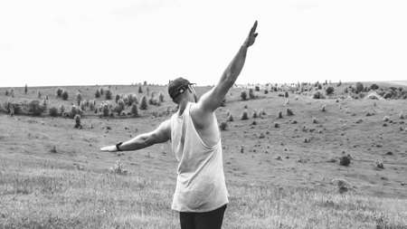 A man in a field is copying an airplane. Black-white photo with a guy in a green countryside.の写真素材