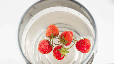Ripe strawberries in water in a glass. Top view, close-up.の写真素材