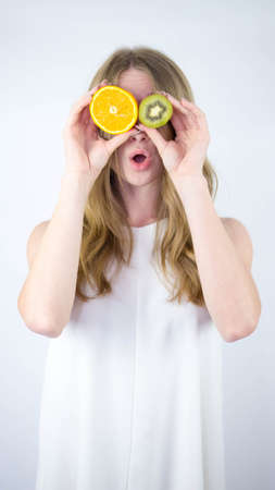 Girl with fruit, close your eyes with ripe fruit, hold an orange, kiwi in your hand.Pretty and...