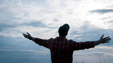 A young man looks into the sky, hands are on the side, the guy pretends to be an airplane, a beautiful landscape and the silhouette of a guy, close-up.の写真素材