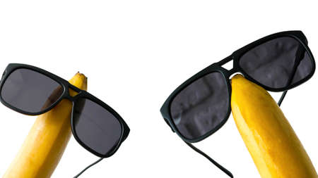 Sun goggles dressed on a banana head, funny fruits in glasses, isolated on white, close-upの写真素材