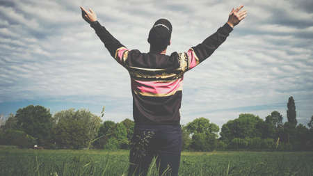The guy looks at the sky, holding hands to the sides. The young man in the field and hands to the sides. The man looks up to the sky, the dreamy man. The man pretends to flyの写真素材