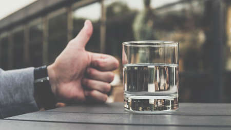Mineral water in a glass on a bar in a restaurant in a cafe in a bar, a man points his thumb at drinking water in a glass.の写真素材