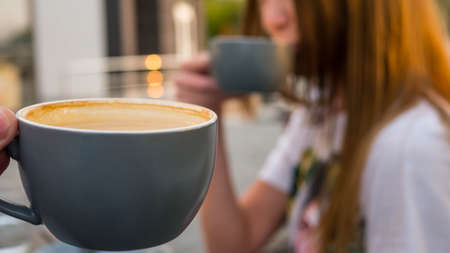 Girl enjoying a cup of cappuccino on a blurred background.