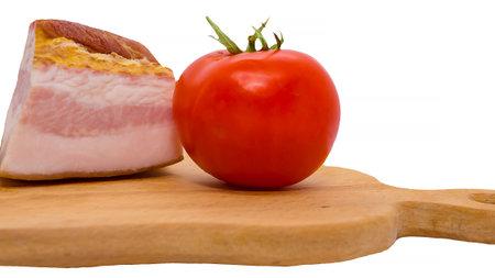 Bacon with fresh tomato on a wooden tray, food isolated on a white background, slice of smoked bacon.の写真素材