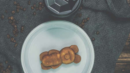 Delicious pastries with cappuccino in a plastic glass, morning breakfast, a glass of coffee with figured cookies, an edible teddy bear. Roasted coffee beans.の写真素材