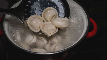 Cook dumplings in a saucepan, homemade dumplings. Stir the dumplings with a scoop.の写真素材
