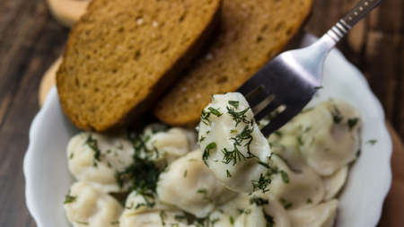 Homemade dumplings in a plate on a wooden tray, dumplings on a fork, delicious food.の写真素材