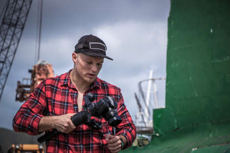 A videographer with a camera in his hands, a man shoots a video, a photographer at work. A young man...