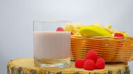 Fruit yogurt in a glass on a wooden board and with fruits in a basket.の写真素材