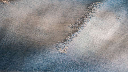 Denim background from light blue fabric. Blue ripped jeans close-up. Denim stylish. Textile.の写真素材