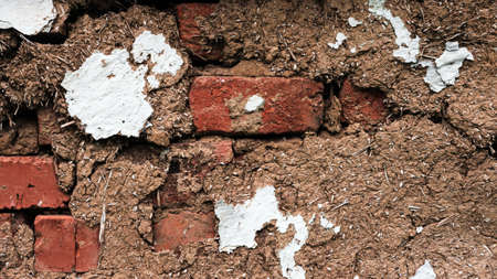Ancient wall of an old rural house. Texture of a wall made of clay and peeling paint.の写真素材