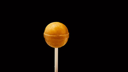 Candy cane yellow lollipop on a black background.の写真素材