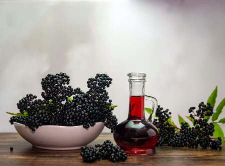 Medicinal herbs from elderberry in a bottle, ripe black berry in a plate, squeezed juice from elderberry.の写真素材