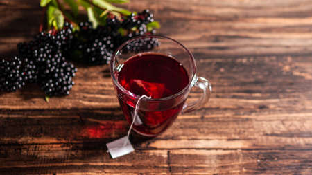 Red tea with herbs from berries, homeopathic treatment with elderberry. Ripe black berries with a mug of tea.の写真素材