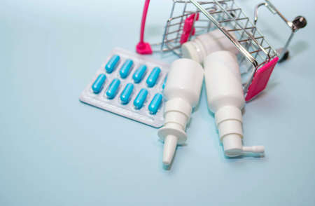 Pills and medicines on a blue background, nasal spray, remedy for sore throat top view.の写真素材