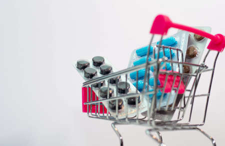 Blue capsules in a plate, medicines in a supermarket basket.の写真素材