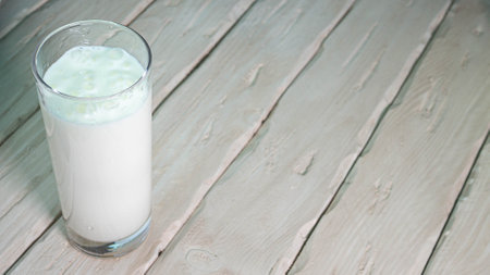 Milk in a transparent glass on wooden boards copy space. Dairy product in a glass.