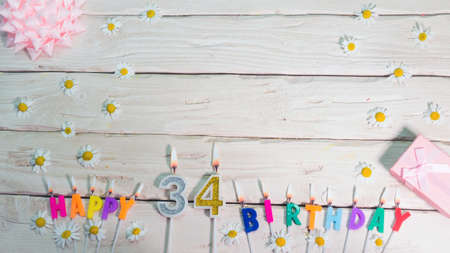 A beautiful card for a birthday in pastel colors in pink shades with a number  34. The decorations of their candles are festive from above, for a couple or a woman with a happy birの写真素材