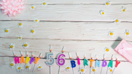 A beautiful card for a birthday in pastel colors in pink shades with a number  56. The decorations of their candles are festive from above, for a couple or a woman with a happy birの写真素材
