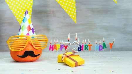 Happy birthday card with number 72. Copy space, beautiful birthday greeting character with mustache in glasses. Decorations with candles from numbers for a birthday.の写真素材