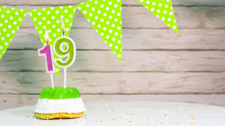 Beautiful festive background with the number 19 with a cake and lit candles, space saving for any holiday. Garland with birthday decorations for a postcard.Decorations are multi-coの写真素材