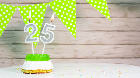 Beautiful festive background with the number 25 with a cake and lit candles, space saving for any holiday. Garland with birthday decorations for a postcard.Decorations are multi-coの写真素材
