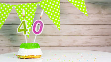 Beautiful festive background with the number 40  with a cake and lit candles, space saving for any holiday. Garland with birthday decorations for a postcard.Decorations are multi-cの写真素材