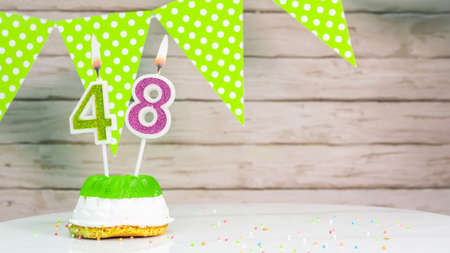 Beautiful festive background with the number 48  with a cake and lit candles, space saving for any holiday. Garland with birthday decorations for a postcard.Decorations are multi-cの写真素材